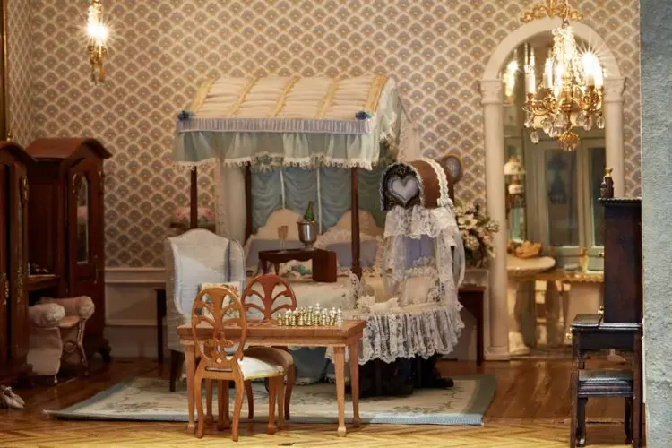 Bedroom with a lace-canopied bed, chandelier and a small chess table