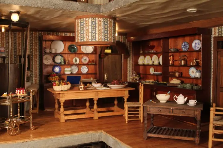 Kitchen with a long wooden table, a hutch full of plates and copper cookware